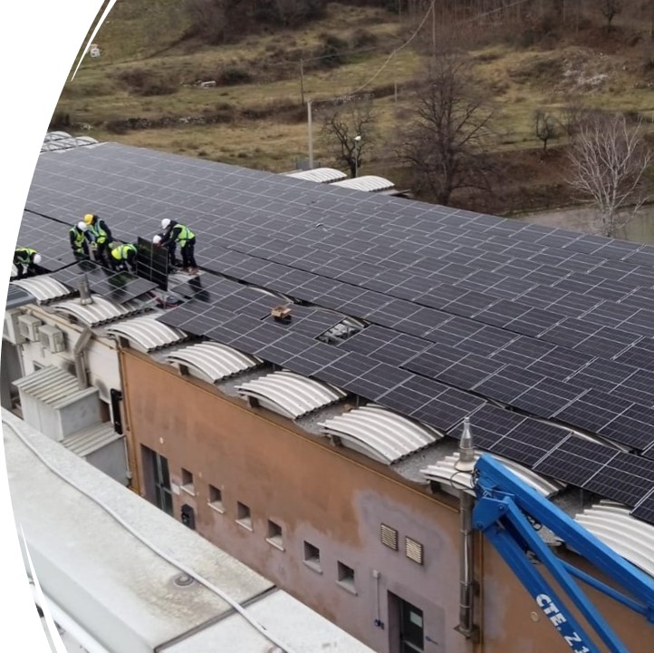 Operai in fase di installazione di un ampio impianto fotovoltaico sul tetto di un edificio commerciale/industriale.