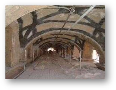 Interno di una volta a botte durante i lavori di rinforzo strutturale, con bande scure di fibra di carbonio applicate per la messa in sicurezza antisismica a Bologna.